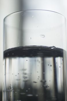 Glass of sparkling water soft drink closeup on carbon dioxide gas bubbles.