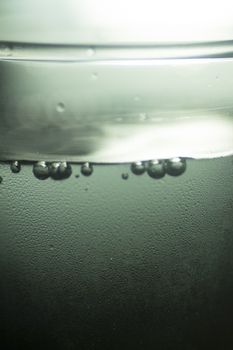 Glass of sparkling water soft drink closeup on carbon dioxide gas bubbles.