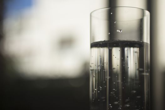 Glass of sparkling water soft drink closeup on carbon dioxide gas bubbles.