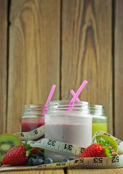 Measuring tape around three flavored smoothies in jars 