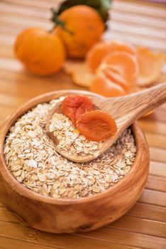 Oat flakes with  dried apricots at wooden plate on wooden background