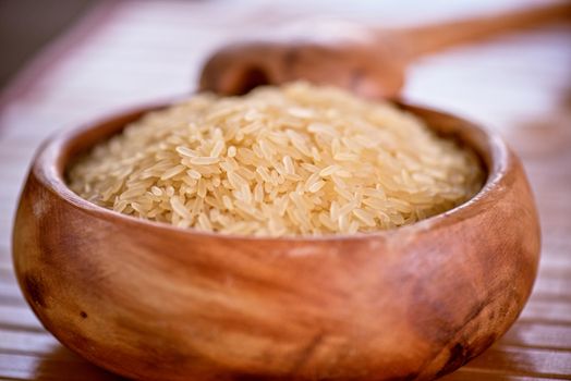 golden rice on wooden plate on wooden background