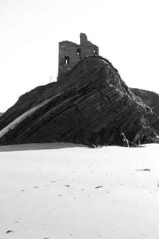 old historic castle on a cliff edge over the beach in Ballybunion county Kerry Ireland in black & white