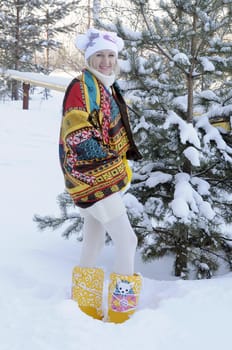 The joyful young woman costs near a pine in park in the winter