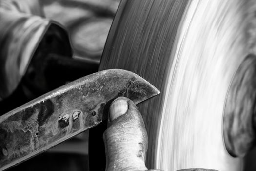 Sharpening a knife blade on a wet sandstone grinding wheel