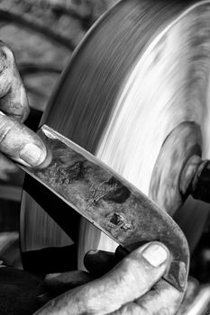 Sharpening a knife blade on a wet sandstone grinding wheel