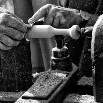 A man using a lathe to carve out a wood product