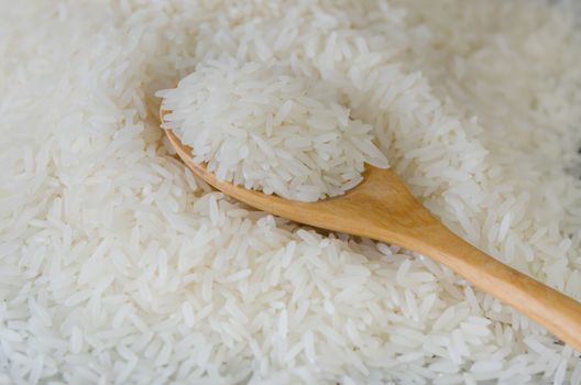 Wooden spoon with rice lying against the background rice