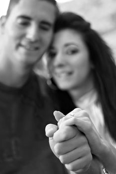 Young happy couple holding a diamond engagement ring.  Shallow depth of field with sharp focus on the ring.