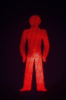 Red man pedestrian stop traffic light photo at night on black background.