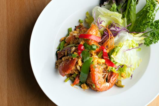 Thai jumbo shrimp salad on a round white plate. Shallow depth of field.