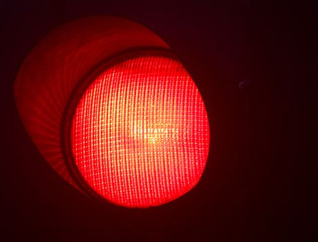 Traffic red stop light photo at night on black background.