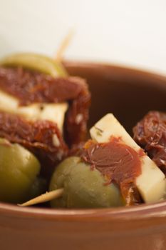 Green olives with cheese and sun dried tomato Spanish tapas bowl on table in Spain.