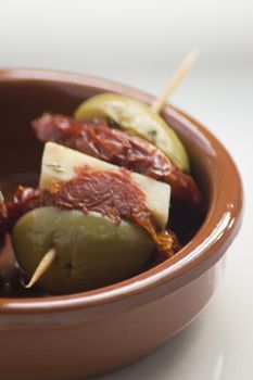 Green olives with cheese and sun dried tomato Spanish tapas bowl on table in Spain.