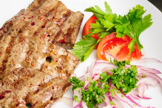 fried beef or pork liver with fresh vegetable salad served on plate