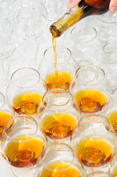 pouring the brandy or cognac into glasses in rows