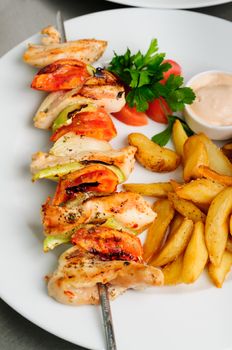 chicken shish kebab on skewers with pepper, fried potato and salad