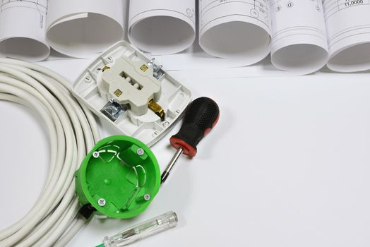 Drawing rolls, wall socket, socket box, power cable, screwdriver, test pen on white surface