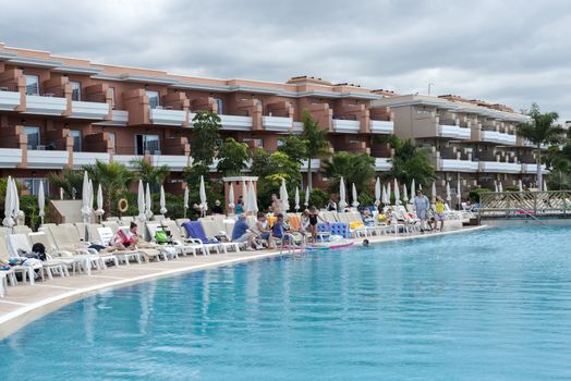 LOS CHRISTIANOS,TENERIFE-NOVEMBER 28, 2014: People enjoy vacation near the swimming pool at resort in Tenerife, on November 28,Tenerife tis one of the popular island of canadian islands.