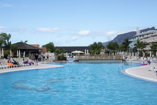 LOS CHRISTIANOS,TENERIFE-NOVEMBER 28, 2014: People enjoy vacation near the swimming pool at resort in Tenerife, on November 28,Tenerife tis one of the popular island of canadian islands.