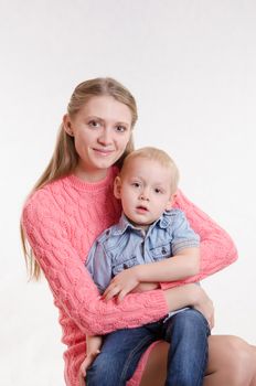 On the lap of a young beautiful girl sits her three year old son