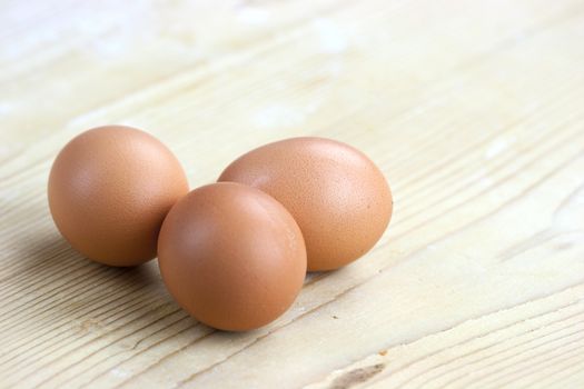 Three white eggs sit on a butcher block counter