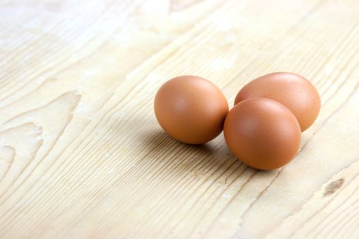 Three white eggs sit on a butcher block counter