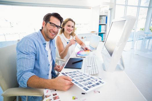 Two happy photo editors working with contact sheets in office