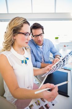 Two happy photo editors working with contact sheets in office