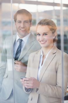 Business people looking at camera through the window at work