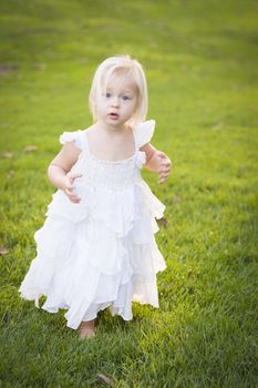 Beautiful Adorable Little Girl Wearing White Dress In A Grass Field.