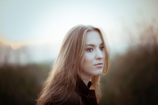 Young brunette girl in late autumn on sunset walking outdoors