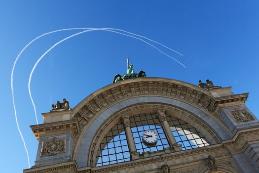 Photo of two jets making trails over the arches and facade of the old Lucerne train station which was destroyed by fire in 1971.