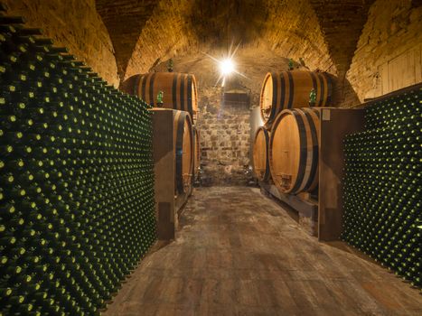 Wine bottles and barrels in a Tuscan winery cellar