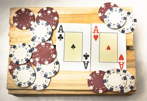 A pair of aces together with a pile of chips on a wooden support