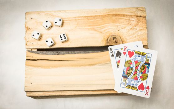 A pair of kings together with dices on a wooden support