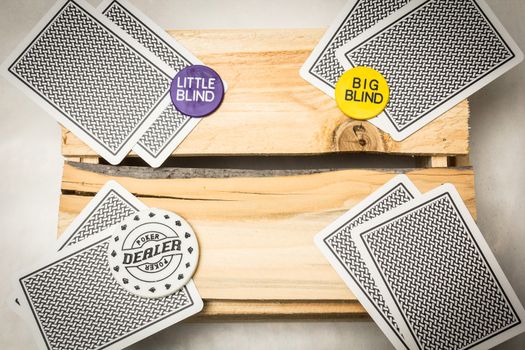 Playing cards lying on a wooden support together with dealer and blind buttons