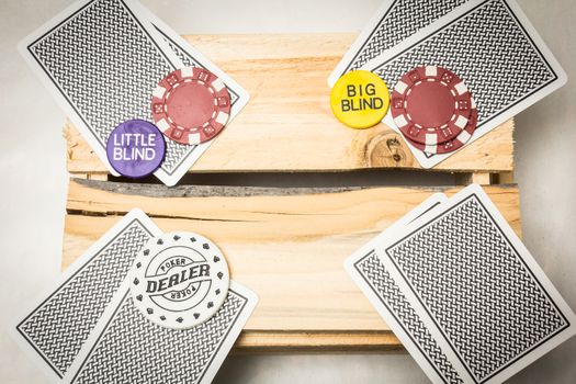 Playing cards lying on a wooden support together with dealer and blind buttons