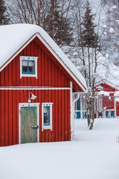 Red wooden Finnish house in winter forest covered with snow