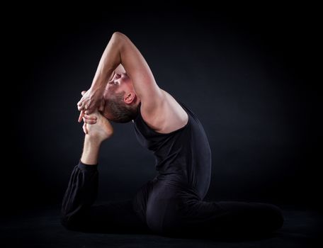 Handsome man doing yoga. Shot on black background