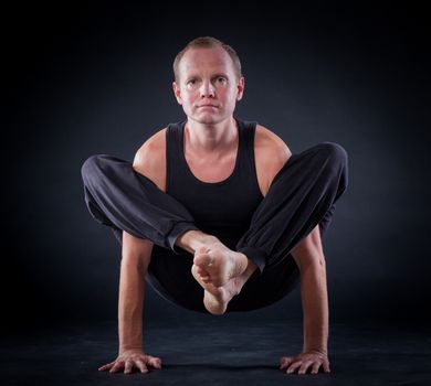 Handsome man doing yoga. Shot on black background