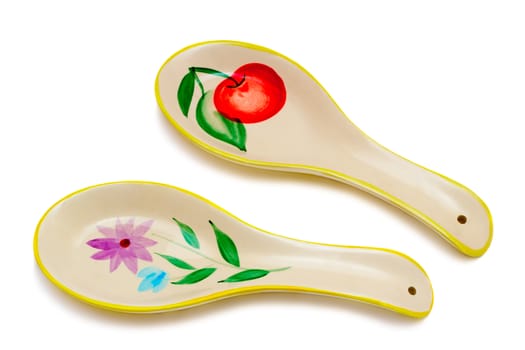 Two large white ceramic spoons, painted. Presented on a white background.
