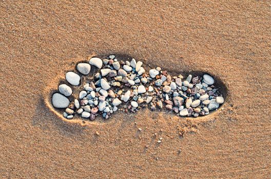 Footstep with small pebbles on the sandy beach