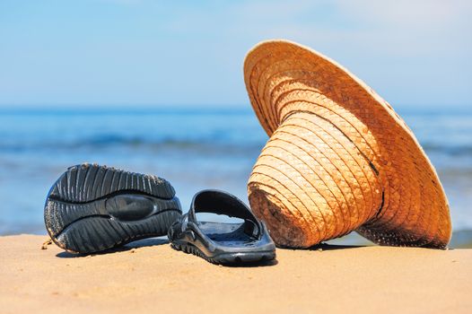 Straw hat and rubber flip-flops on the seashore