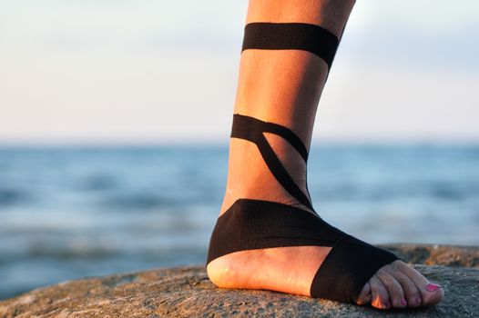 Therapeutic treatment of leg with black physio tape
