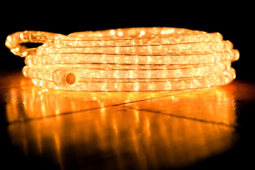 festive tube rope light coiled on a reflective hardwood floor