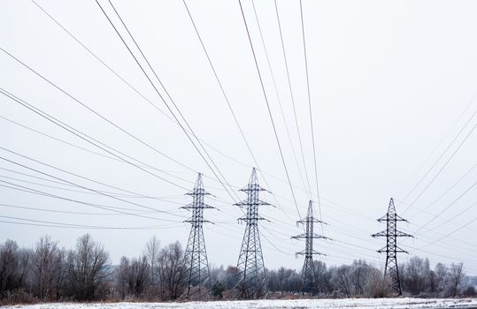 System of electricity pylons and power lines out-of-town in the winter day.