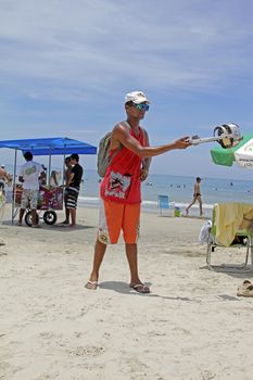 SAO SEBASTIAO, BRAZIL - JANUARY 04, 2015: An unidentified walking vendor with hand-held charcoal oven roasting handmade cheese on a beach in Brazil.