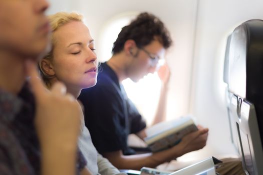 People flying by plane. Interior of airplane with passengers killing time on their seats.