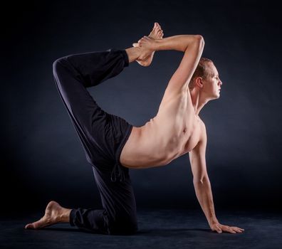 Handsome man doing yoga. Shot on black background